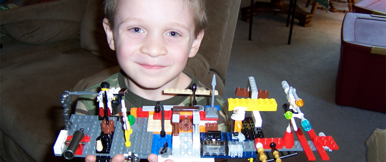 Young boy proudly showing off his lego creation