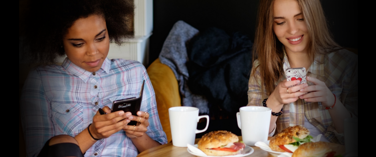 Two women on phones over breakfast